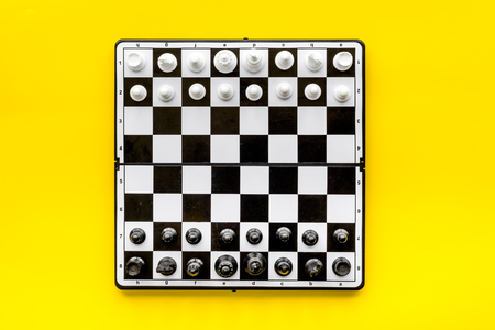 Chess game concept. Chess board with figures on yellow background top view copy spaceの写真素材