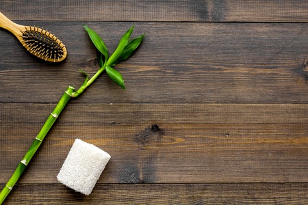 Asian spa procedure with natural ingredients concept. Bamboo branch, spa cosmetics on dark wooden background top view copy spaceの写真素材