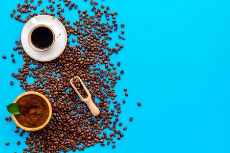 Brown roasted coffee beans scattered on blue background and cup of Americano top view mockupの写真素材