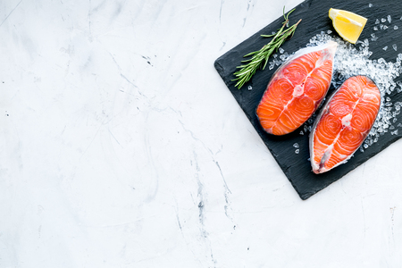 Raw salmon fish on black plates for cooking steaks on marble restaurant kitchen background top view space for textの写真素材