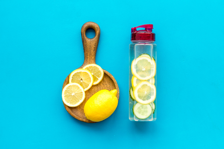 Make detox fruit water. Slices of lemon and cucumber in bottle on blue background top view copy spaceの写真素材