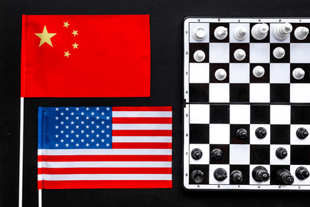 Chess competition concept. Chess board with figures near American and Chinese flags on black background top viewの写真素材