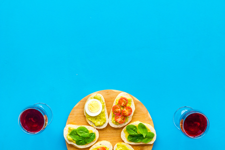 Healthy snacks. Set of toasts with vegetables like avocado, guacamole, rocket, cherry tomatoes on blue background top view.の写真素材