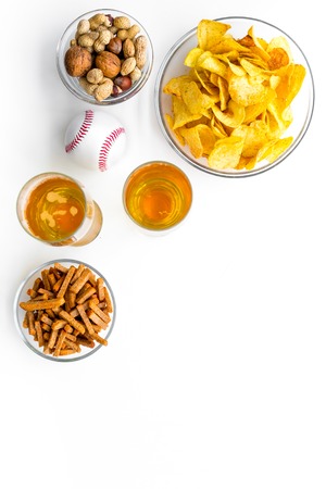 Snacks for watching american football on TV. Watching sports. Chips, nuts, rusks near beer and ball on white background top view copy spaceの写真素材