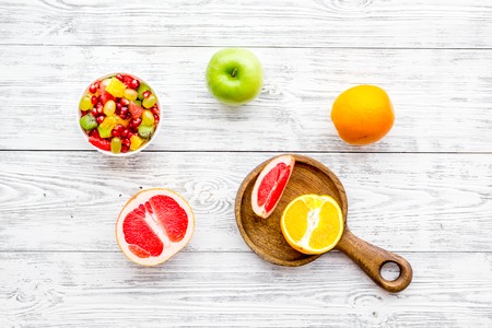 Food rich by vitamins and fiber. Healthy food. Fruit salad near fresh fruits on white wooden background top view.の写真素材