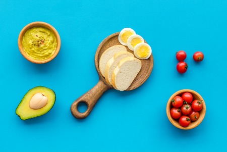 Healthy breakfast. Toasts with vegetables and guacamole on blue background top viewの写真素材