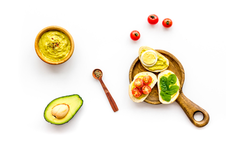 Make avocado bruschettas. Toasts with vegetables and guacamole on white background top viewの写真素材