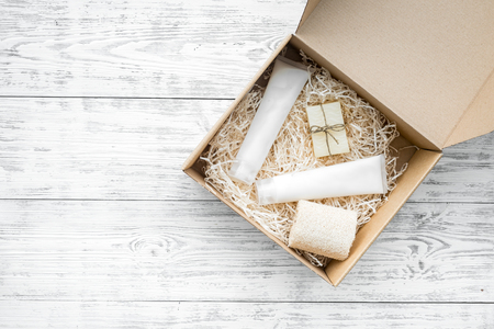 Delivery. Cardboard box with cosmetics on white wooden background top view space for textの写真素材