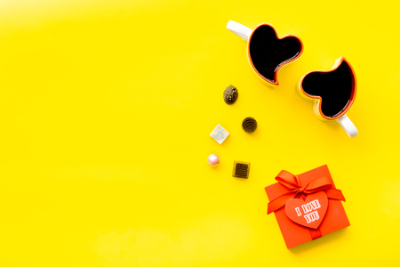 Gift for Valentine's day. Gift box with text I love you and heart-shaped sweets on yellow background top view.の写真素材