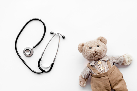 Children's doctor concept. Teddy bear toy and stethoscope on white background top view.の写真素材