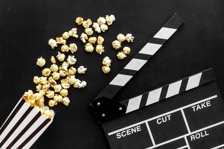 Film watching concept. Clapperboard and popcorn on black background top view.の写真素材