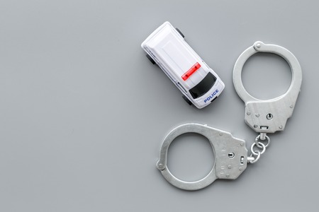 Police concept. Police car toy and handcuff on grey background top view.の写真素材