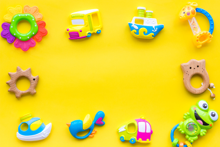 Handmade toys for newborn babies, plastic and wooden rattle on yellow background top view.の写真素材