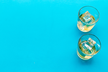 Glass of whiskey with ice on blue background top view copy spaceの写真素材