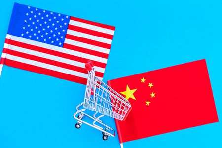 USA and China trade war. American and Chinese flags near shopping chart on blue background top view copy spaceの写真素材