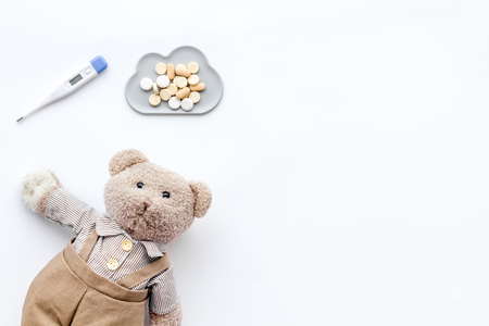 Childhood diseases concept. Treatment of children.Teddy bear toy, thermometer and pills on white background top view.の写真素材