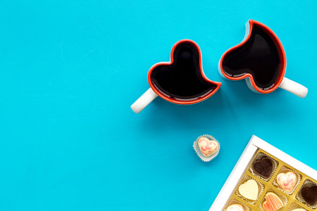 Dating on Valentine's day concept. Heart-shaped mugs and sweets on blue background top view.の写真素材