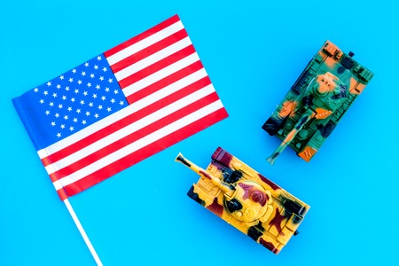 War, military threat, military power concept. USA. Tanks toy near American flag on blue background top view.の写真素材