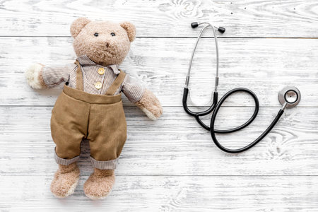 Children's doctor concept. Teddy bear toy and stethoscope on white wooden background top view copy spaceの写真素材