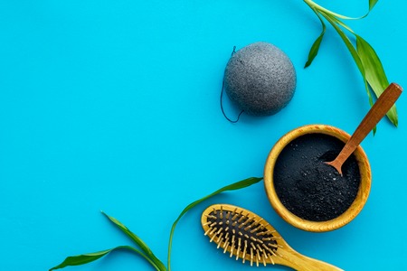 Hair care, hair spa. Cosmetics based on bamboo charcoal powder near comb on blue background top view space for textの写真素材