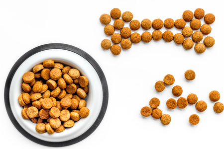 Dog food. Dry food in shape of bone near bowl on white background top viewの写真素材
