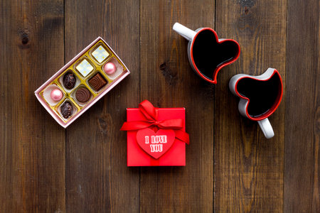 Valentines day concept. Sweets, red gift box, heart-shaped mugs on dark wooden background top viewの写真素材