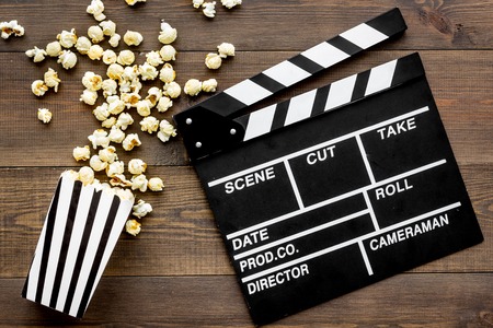 Film watching concept. Clapperboard and popcorn on dark wooden background top view.の写真素材