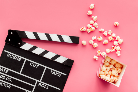 Film watching concept. Clapperboard and popcorn on pink background top view copy spaceの写真素材