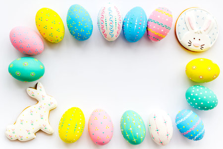 Colorful Easter eggs frame on white background top view.