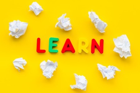 Learn concept. Word learn lined with colorful letters near crumpled paper on yellow background top view.の写真素材