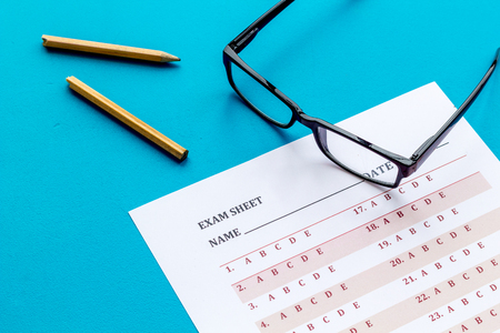 Take the exam. Exam sheet near glasses and pencil on blue backgroundの写真素材