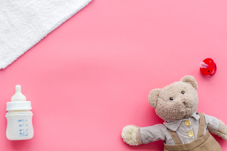 Food for babies concept. Teddy bear toy near small bottle with food on pink background top view copy spaceの写真素材