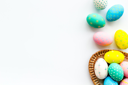 Easter traditions. Colorful Easter eggs in basket on white background top view copy space borderの写真素材