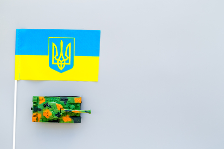 War, military threat, military power concept. Ukraine. Tanks toy near Ukrainian flag on grey background top view copy spaceの写真素材
