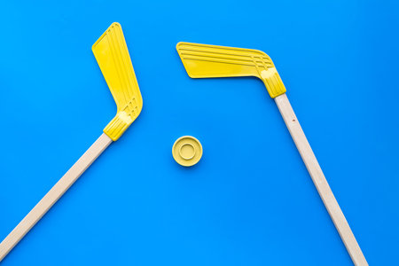 Ice hockey stick and puck on blue background top view.