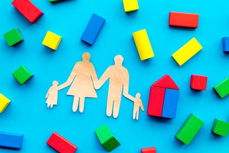 House building concept. Family cutout among colorful toy bricks on blue background top viewの写真素材