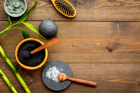 Skin cleansing and detox. Bamboo charcoal powder cosmetics on dark wooden background top view space for textの写真素材