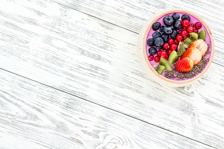 Superfoods. Acai smoothie bowl with fresh fruits, berries, chia seeds on white wooden background top view space for textの写真素材