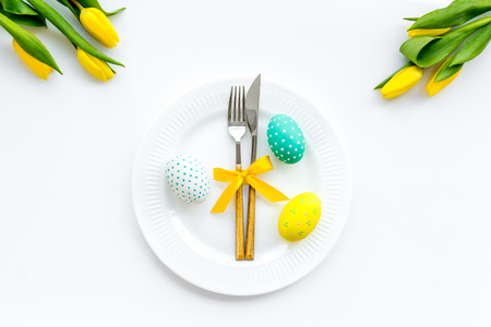 Festive Easter table decorated with tulips. Tableware and painted eggs on white background top viewの写真素材