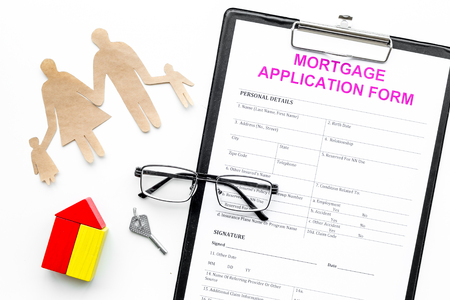 Mortgage concept. Mortgage application form near key and house made of constructor, family cutout on white background top viewの写真素材