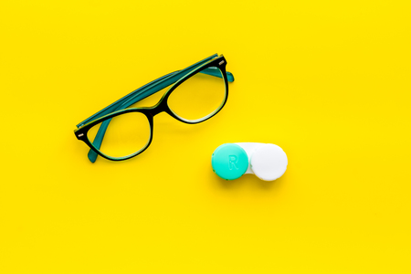 Eyes care. Glasses with transparent lenses and contact lenses on yellow background top view.の写真素材