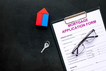 Mortgage concept. Mortgage application form near key and house made of constructor on black background top view space for textの写真素材