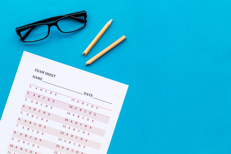 On the exam. Exam sheet, answer near glasses and pencil on blue background top view copy spaceの写真素材