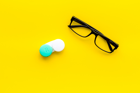 Eyes care. Glasses with transparent lenses and contact lenses on yellow background top view copy spaceの写真素材