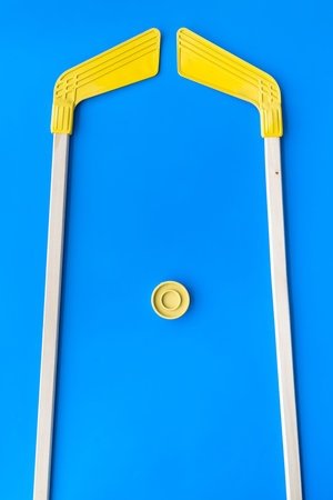 Ice hockey stick and puck on blue background top view copy space