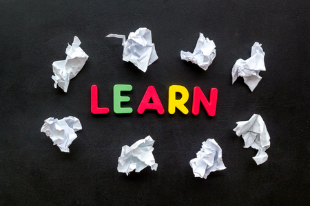 Learn concept. Word learn lined with colorful letters near crumpled paper on black background top viewの写真素材