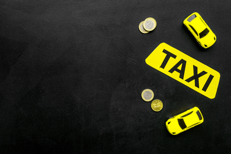 Taxi operator concept. Chip service. Price of services. Sign taxi near car toy and coins on black background top view.の写真素材