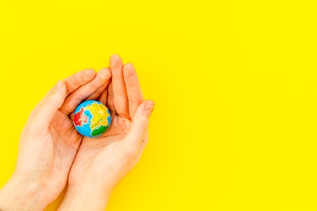 SOS Save the planet concept. The earth in hands on yellow background top view flat lay space for textの写真素材