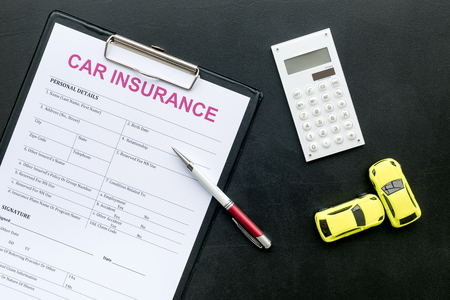 Car insurance form near toy, calculator, pen on black background top viewの写真素材