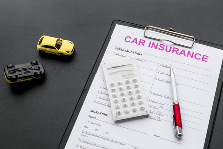Car insurance form near toy, calculator, pen on black backgroundの写真素材